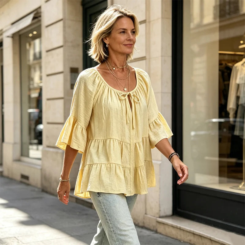 Elegancka damska bluzka z falbankami i wiązaniem przy dekolcie, rękawami 3/4 typu dzwon, o fakturze materiału i w stylu boho-chic, w swobodnym fasonie z baskinką.